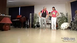 A young dancer teaches an elderly man some dance moves